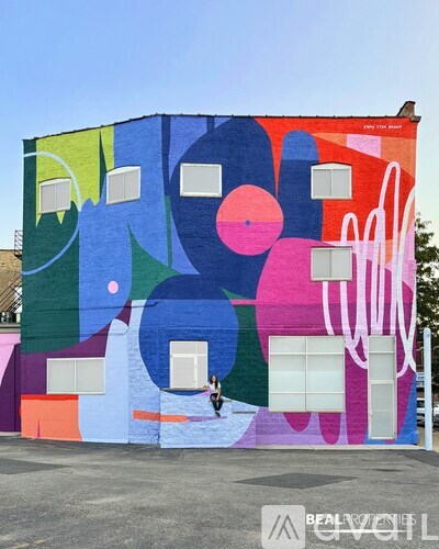 A person is standing in front of a colorful mural on a building.