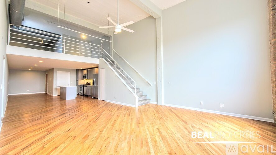 A spacious room with wooden flooring and a staircase leading to another level.