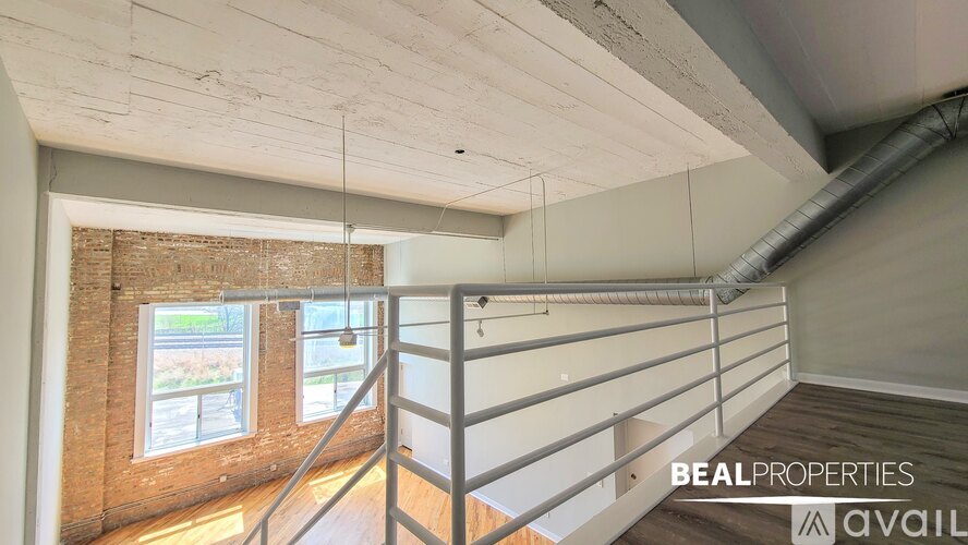 A BEALPROPERTIES sign is hanging from the ceiling of a room with a window and a staircase.