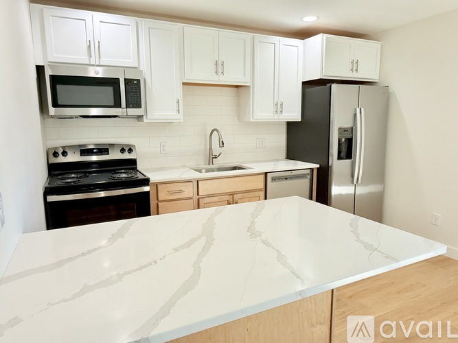 A kitchen with a marble countertop and white cabinets.