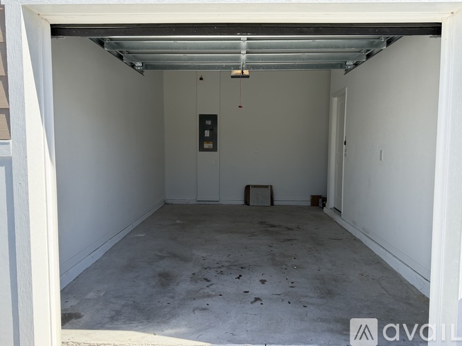 A white garage with a door open and a concrete floor.