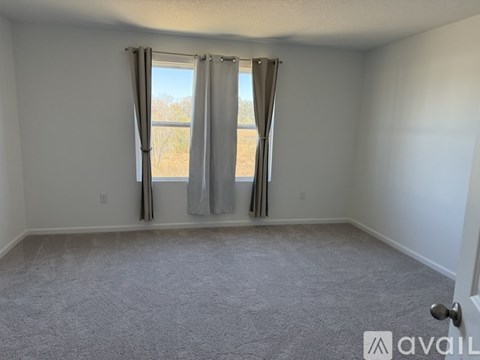 A room with a carpeted floor and a window with curtains.