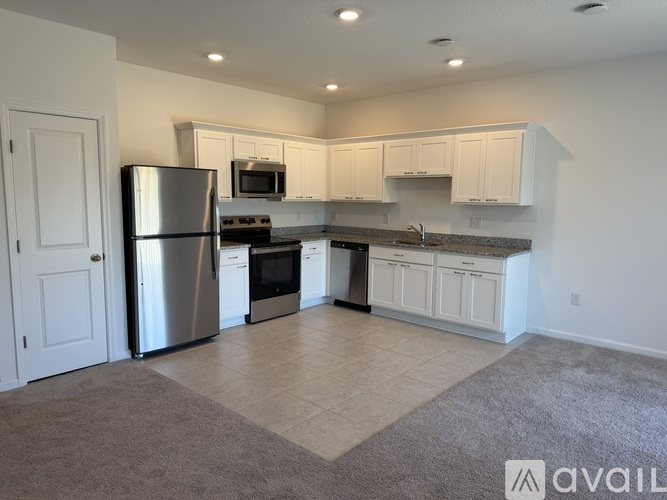 A kitchen with white cabinets and a stainless steel refrigerator.