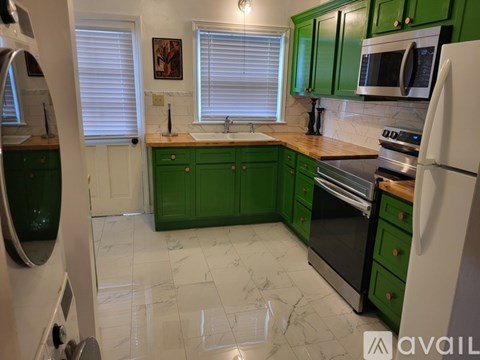 A kitchen with green cabinets and a white refrigerator.