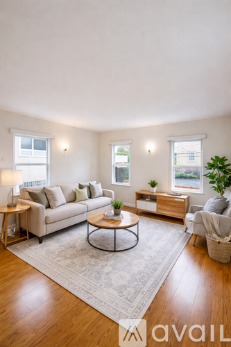 A living room with a couch, coffee table, and two windows.