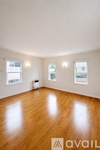 A room with wooden floors and two windows.