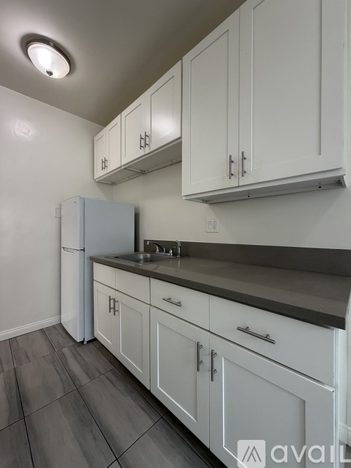 A kitchen with white cabinets and a grey countertop.