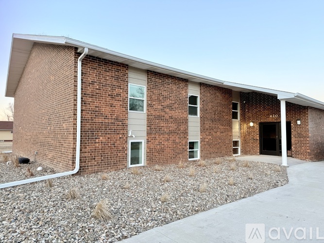 A brick building with a white roof and a gravel driveway in front.