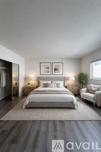 A well-lit bedroom with a large bed and a chair.