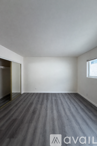 A room with wooden flooring and a window on the right side.