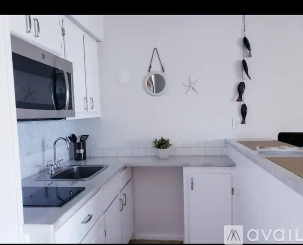 A kitchen with white cabinets and a black microwave.
