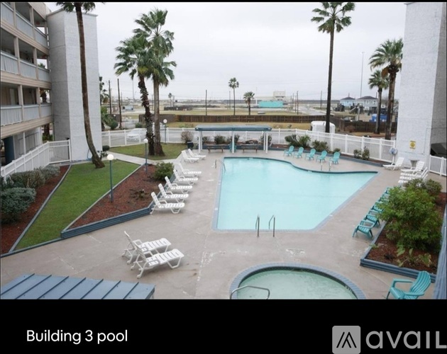 A pool area with chairs and a building in the background.