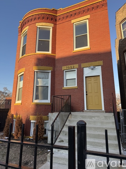 A red brick building with a yellow door and windows.