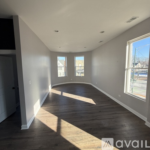 A spacious room with wooden floors and large windows.