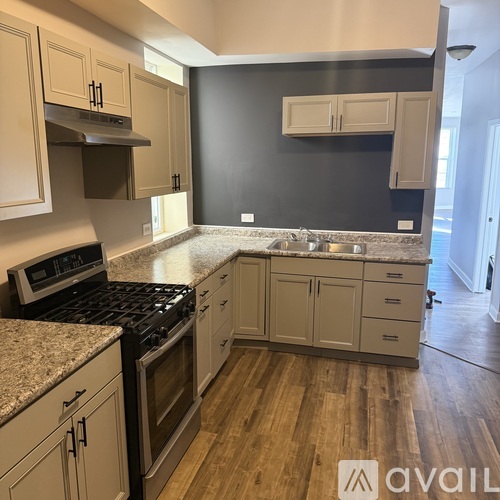 A kitchen with a black wall and wooden floors.