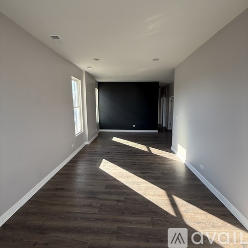 A long, empty room with wooden floors and white walls.