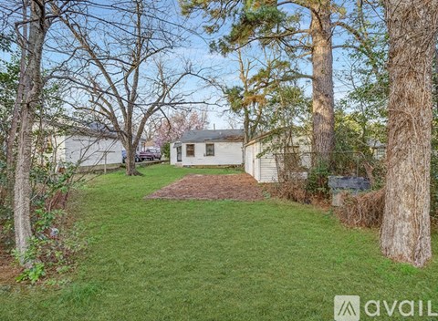 A backyard with a tree and a house in the background.
