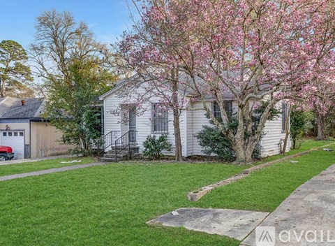 A house with a tree in bloom in front of it.