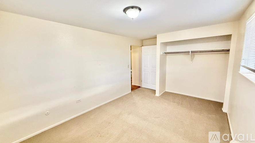 A spacious room with a door on the left and a closet on the right.