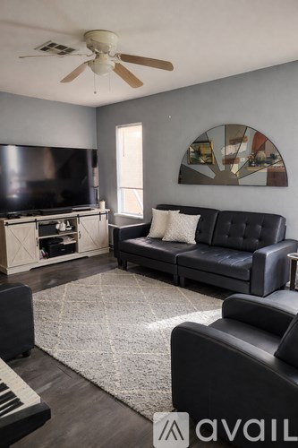 A living room with a black couch and a television.
