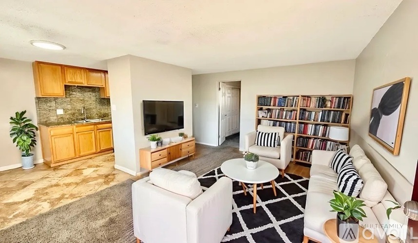 A living room with a white couch, a coffee table, a bookshelf, and a television.