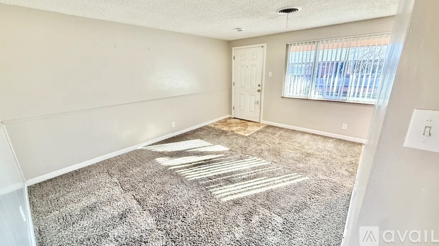 A room with a carpeted floor and a door leading to a balcony.
