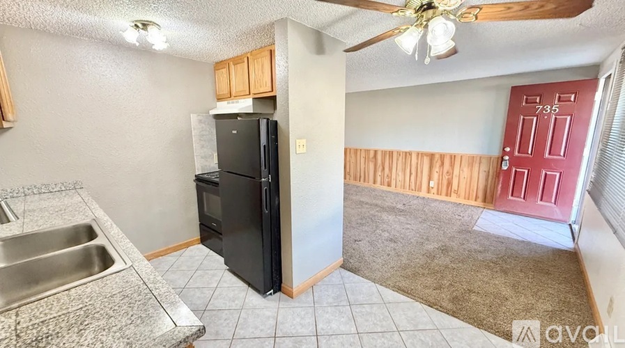 A kitchen with a black refrigerator and a red door.