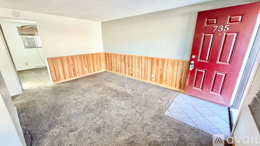 A room with a red door and a wooden wall.