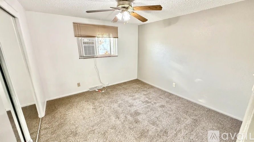 A room with a ceiling fan and carpeted floor.