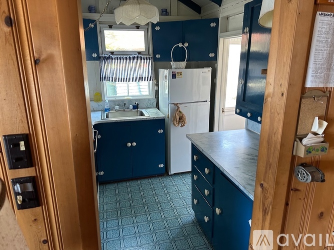 A kitchen with a white fridge and blue cabinets.