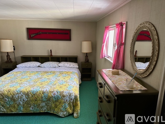 A bedroom with a bed, dresser, and mirror.