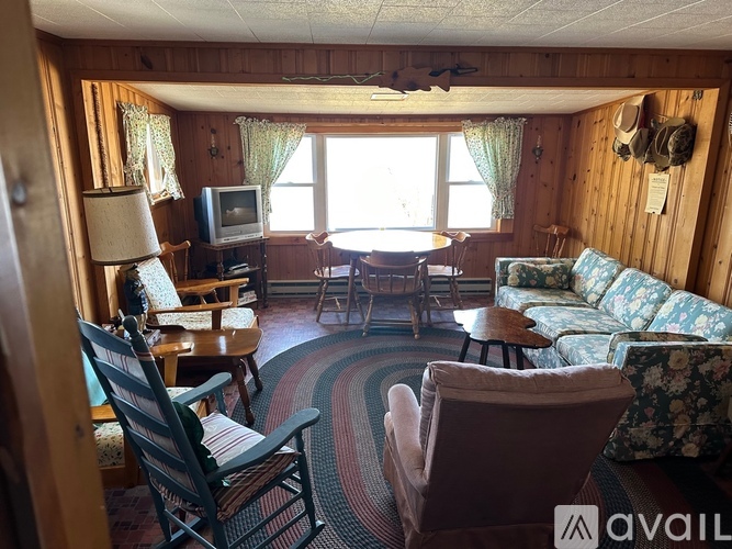A living room with a couch, chairs, and a television.