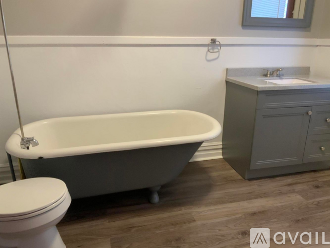 A white bathtub sits next to a toilet in a bathroom.