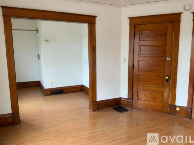 A room with a wooden door and a white wall.