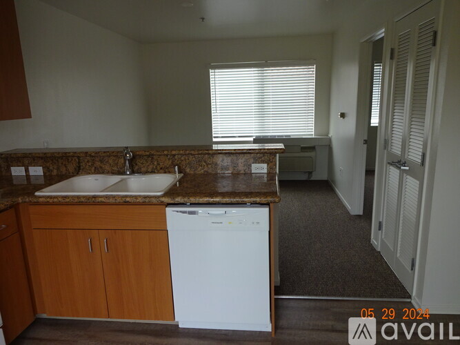 A kitchen with a white dishwasher and wooden cabinets.