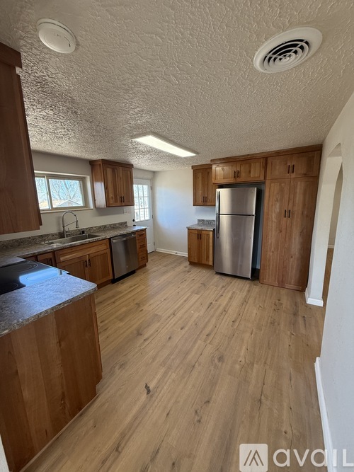 A kitchen with wooden cabinets and a stainless steel refrigerator.