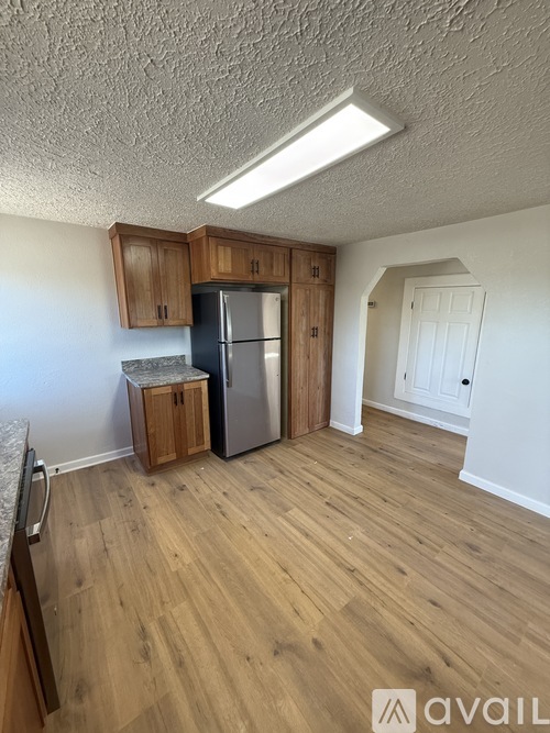 A kitchen with wooden floors and a refrigerator.