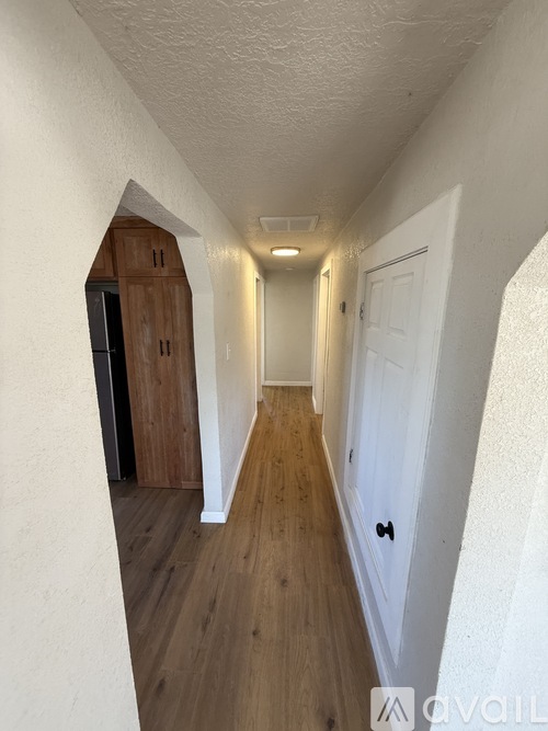 A long hallway with a cabinet and a door at the end.