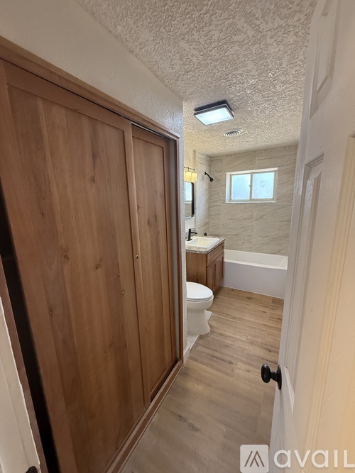 A bathroom with a toilet, sink, and wooden door.