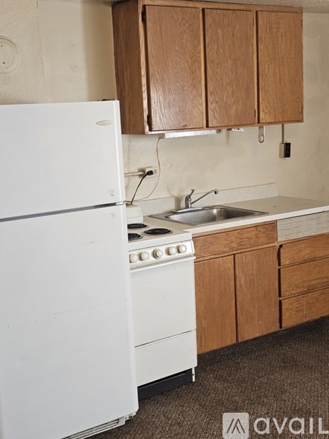 A white fridge and stove in a kitchen with brown cabinets.