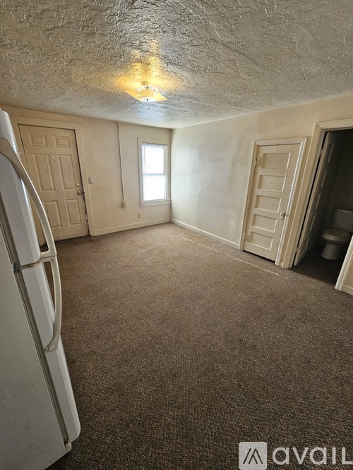 A room with a carpeted floor, a door, and a window.