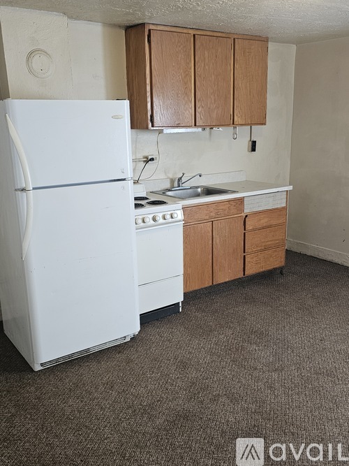 A white refrigerator is in a kitchen with brown cabinets.