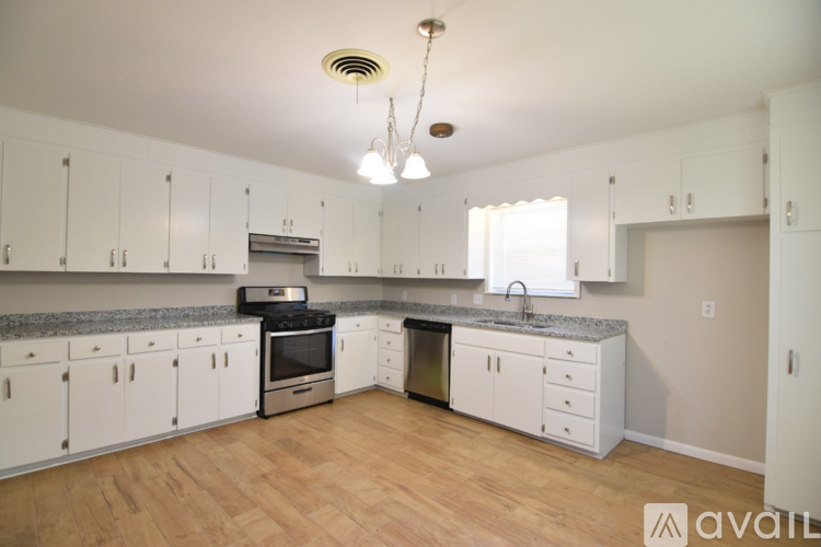 A kitchen with white cabinets and a wooden floor.