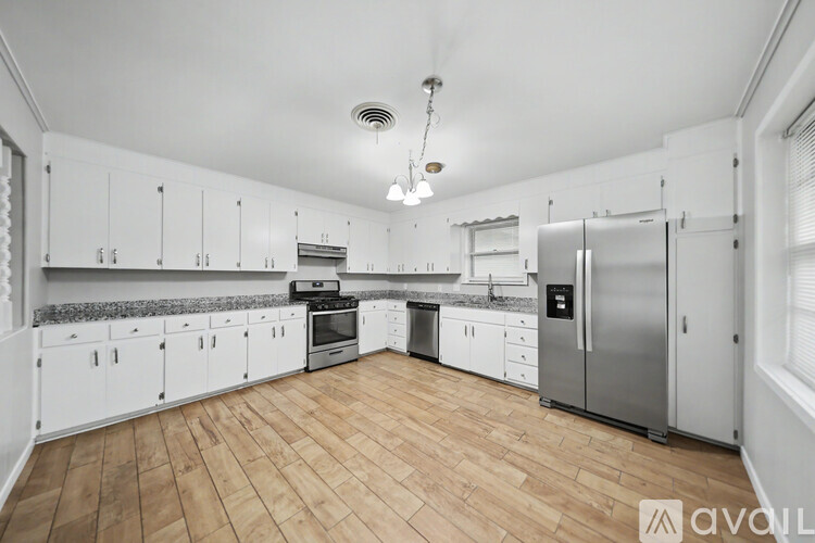 A kitchen with white cabinets and a wooden floor.
