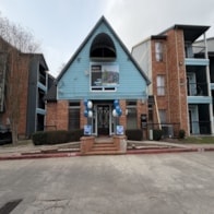 A blue building with a red brick base in front of a brown building.
