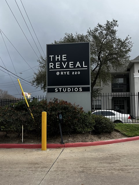 A sign for The Reveal Studios is displayed in front of a building.