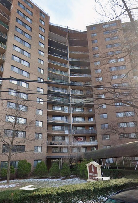 A small red and white house is in front of a large apartment building.