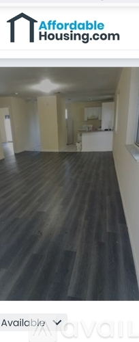 A room with wooden flooring and a white wall.