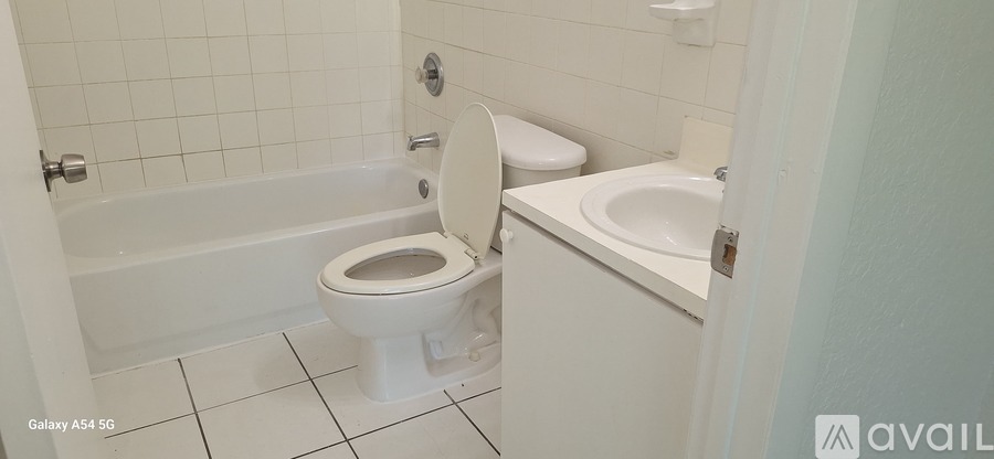 A white toilet with a white bath tub in a bathroom.