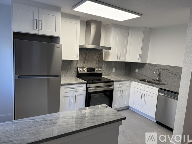 A modern kitchen with a stainless steel refrigerator and a marble countertop.